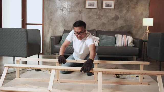 Asian forgetful man self-assembling furniture with DIY tools, forgetting and finding rubber mallet hammer, home improvement, expert craft installation, wooden hobby workshop, mature active lifestyle.
