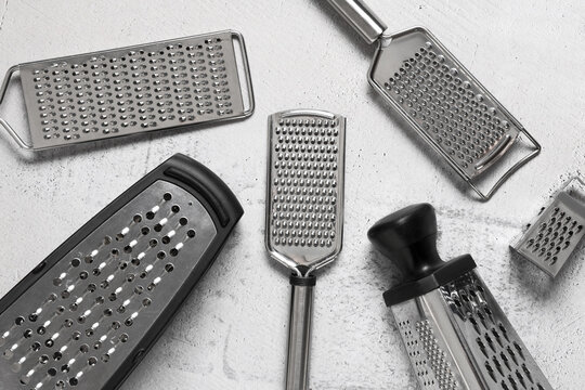 Culinary preparation and food processing, collection of various metal kitchen graters for cooking and gourmet meal preparation on a textured surface