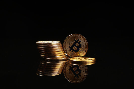 Cryptocurrency investment and digital finance, stack of gold bitcoin coins with reflection on black background for blockchain technology and wealth growth