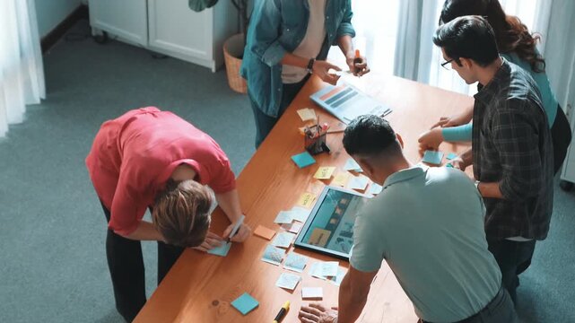 Top view of manager writing idea on sticky notes and explain idea about web design. Professional marketing team or programmer brainstorming idea while looking at tablet with color palette. Symposium.
