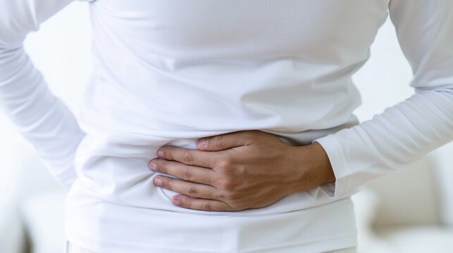 Person holding abdomen while standing indoors at home during the day