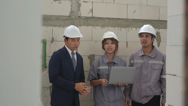 Structural engineer discusses construction details with architect and worker while reviewing building progress during teamwork at unfinished project site.