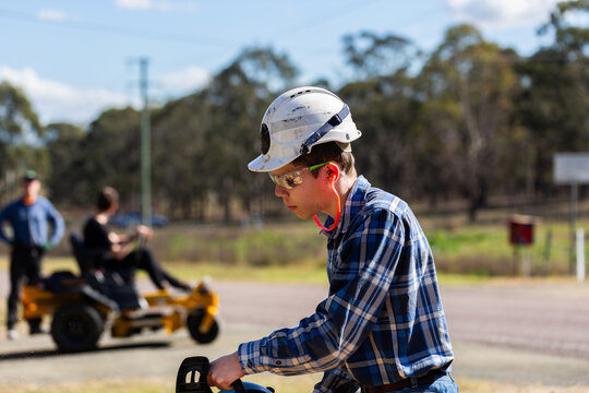 young man chainsawing up branch of gum tree for firewood