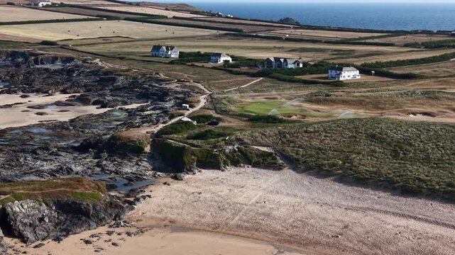 Constantine Bay, United Kingdom - 23 July 2026: Aerial view of the sandy beach, rocky shoreline, and surrounding coastal fields with houses.