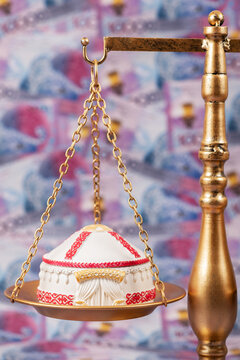 A symbolic Kazakh yurt resting on a scale against a background of 10,000 Kazakhstani tenge banknotes.