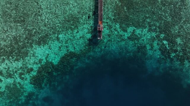Kecamatan Komodo, Nusa Tenggara Timur, Indonesia - 09 September 2026: Aerial view of Kanawa Island jetty extending into vibrant turquoise coral reefs and deep blue ocean waters.