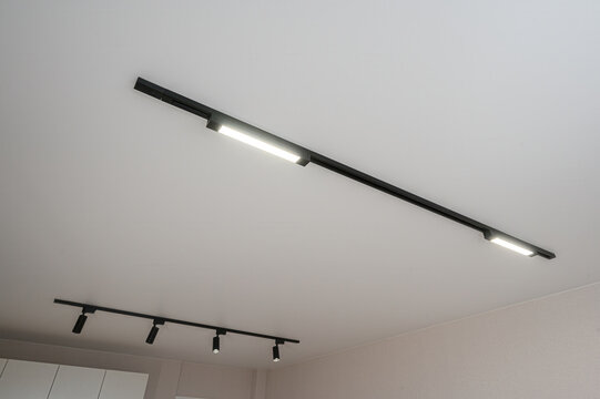 Modern ceiling lighting: black magnetic track, linear LED fixtures, adjustable spotlights, minimalist design, sleek profile, directional illumination, clean aesthetic