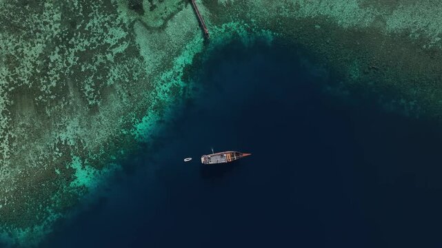 Kecamatan Komodo, Nusa Tenggara Timur, Indonesia - 09 September 2026: Aerial view of traditional wooden boats anchored in the clear turquoise waters near the coral reefs of Kanawa Island.