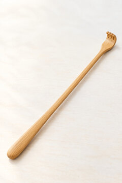 Wooden Backscratcher with Curved Hand Shaped Tip on a Plain Background