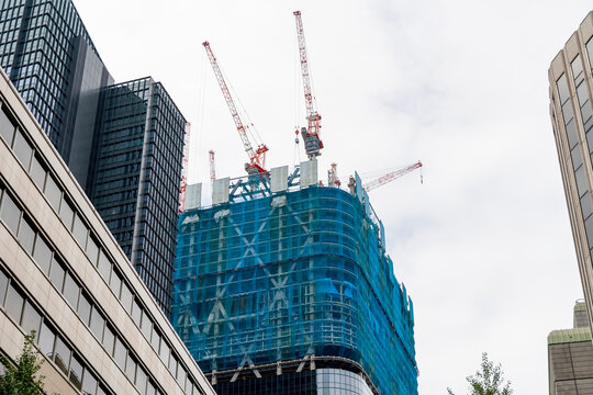 Construction site of an urban high-rise building with cranes and blue sheets