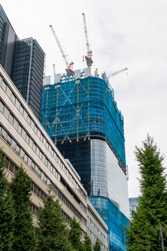 Completed modern office building standing next to a high-rise building under construction