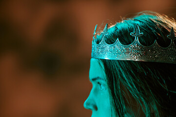 Obraz premium Young adult Caucasian wearing crown looking away, symbolizing leadership, royalty and power. Suitable for fantasy media and storytelling promotions, close up