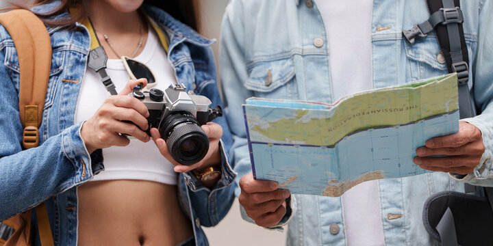 Asian tourists with map and camera for travel planning and navigation