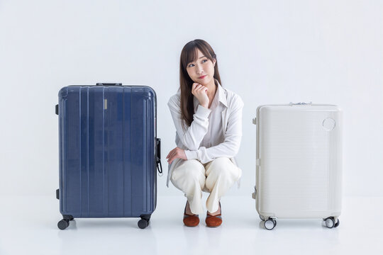 キャリーバッグの間に座り大きさを比較する女性