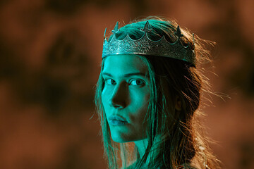 Obraz premium Portrait of young adult Caucasian woman wearing silver crown and looking at camera. Visual represents royalty, power and leadership concepts for fantasy game marketing