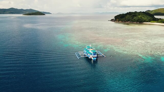 Topical drone shot of a expedition boat in the Philippines next to a remote topical island