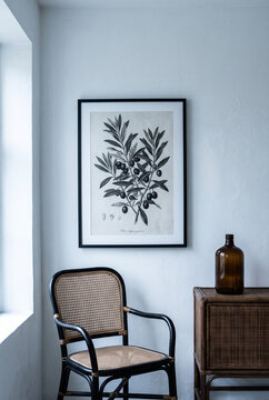 Minimalist scandinavian interior with botanical artwork and rattan chair