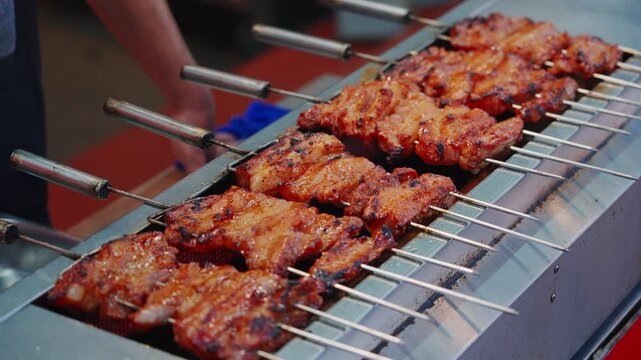 The barbecue stall owner is sorting the rows of barbecued pork