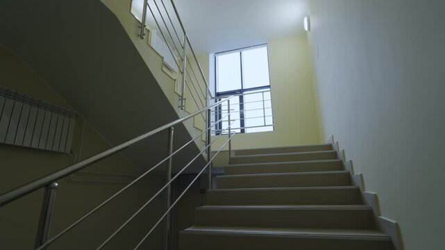 Daylight filters through upper window frame illuminate concrete step treads. Clean architectural design connects building floor levels