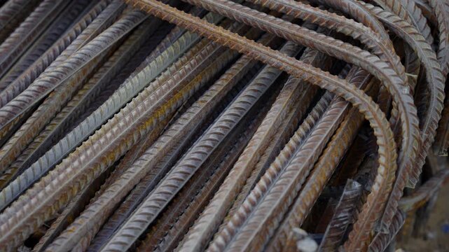 Industrial steel rebars display ribbed surface textures and metallic sheen. Raw building materials await structural concrete reinforcement