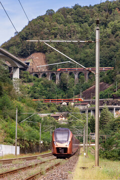 Red trains pass the historic Gotthard spiral loop tunnels, built in the 19th century, to overcome about 200 meter height difference.