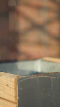 Close up of metal container with wooden sides showing slight camera movement and soft lighting. background remains consistently blurred emphasizing texture detail on both wood and rusted