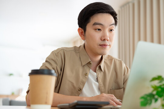 Young Asian man working on laptop at home