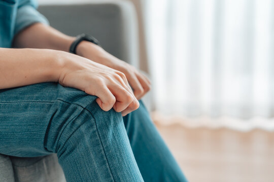 Closeup legs shaking in a guy in blue jeans. Uncontrollable leg shaking. Severe stress in a guy. A man is worried while sitting on a sofa. Health problems and sickness