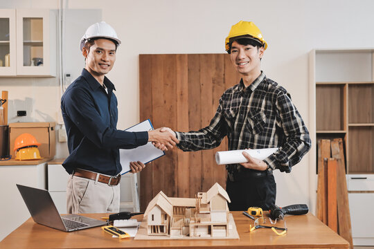 Asian architect and engineer team checking architectural house model using measuring tape on the table at office studio.