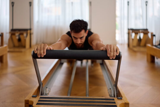 Close up of athlete practicing on reformer machine in Pilates studio.