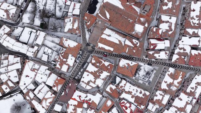 Aerial view of snow-covered terracotta rooftops and narrow streets in the historic village of Pescocostanzo, Abruzzo, Italy.