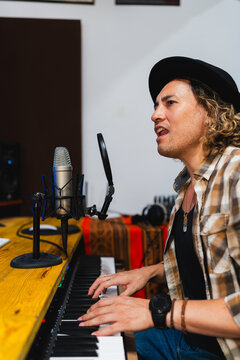 Male musician singing, playing keyboard in studio