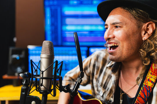 Male musician singing into microphone recording music