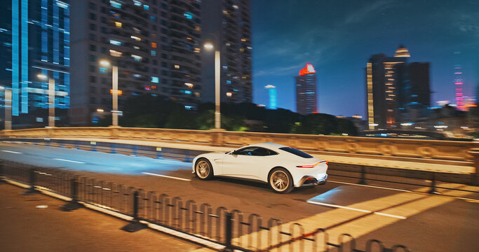 White supercar in fast motion at night. urban street scene with moving cars and modern architecture illuminated at night