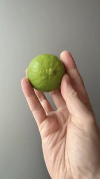 Whole Green Lime Held in an Open Hand Vertical Video