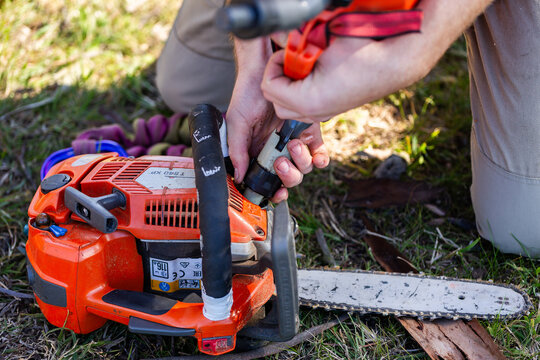 young tradesman apprentice refilling chainsaw fuel