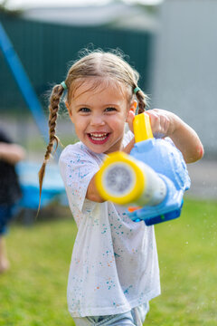 Happy little girl holding bubble blower in backyard during water play fun