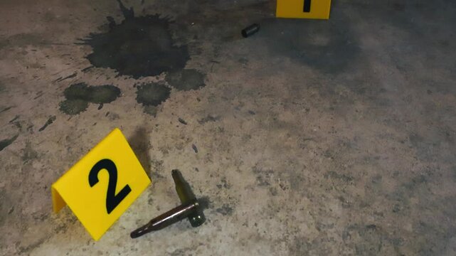 Yellow evidence markers indicating the location of spent bullet casings and rifle cartridges on a dusty, stained concrete floor, depicting a forensic investigation at an active crime scene