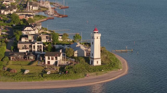 Cinematic aerial view of Strib Lighthouse and the surrounding coastal homes in Middelfart, highlighting the peaceful Danish shoreline and beautiful Little Belt seascape.