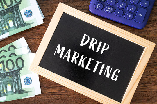 Drip Marketing text on black chalkboard with euro banknotes and calculator on wooden desk, digital marketing concept