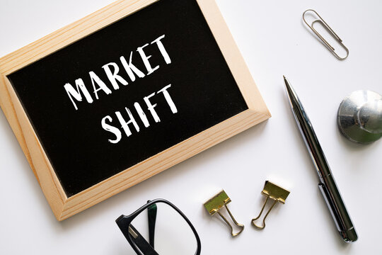 Market Shift text on black chalkboard with pen glasses and office supplies on white background, business strategy concept