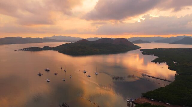 Wide aerial sunset view of boats anchored beside forested islands and long rows of wooden pilings in Coron Bay