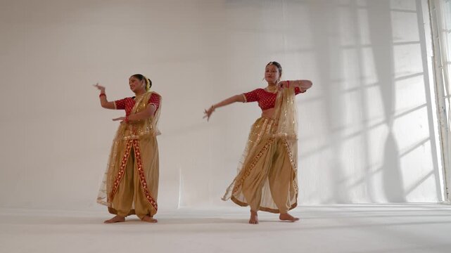 Two Indian women performing a traditional dance in a studio setting