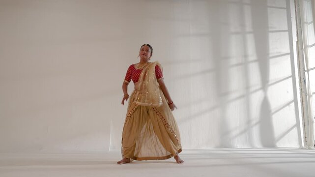 An Indian classical dancer  performing intricate dance movements in a sunlit studio