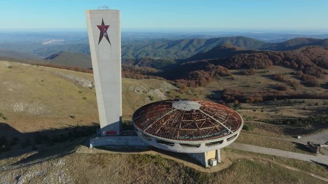 Aerial view of the abandoned socialist Buzludzha monument in Bulgaria. The old concrete structure with its red star sits atop a mountain peak