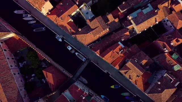 Red tiled rooftops sprawl beneath a drone flying directly above Venice.