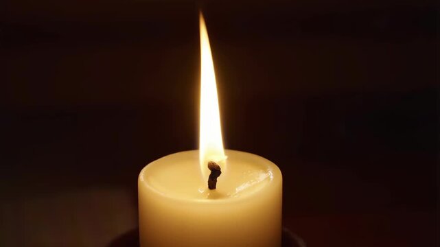 Cinematic close-up of a burning candle flame on a dark background. Slow motion, warm light, selective focus. Ideal for memory, hope, meditation, sadness or romantic design concepts with copy space.
