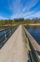 Fototapeta premium Wooden footbridge crossing a scenic lake on a sunny day