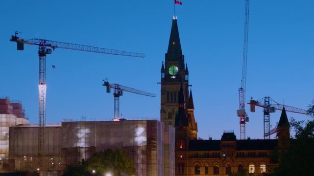Ottawa, Ontario, Canada - September 28, 2026: Peace Tower on Parliament Hill surrounded by construction cranes and scaffolding at night