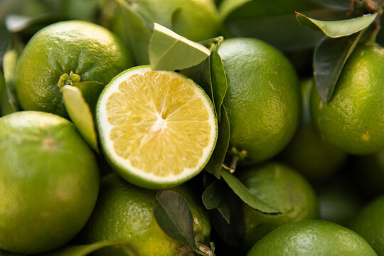 Close‑up of fresh green limes piled together with one lime cut in half